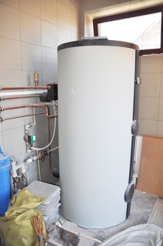A Large White Water Heater is Sitting in a Room Next to a Window — Essential Roofing and Plumbing in Harden, NSW