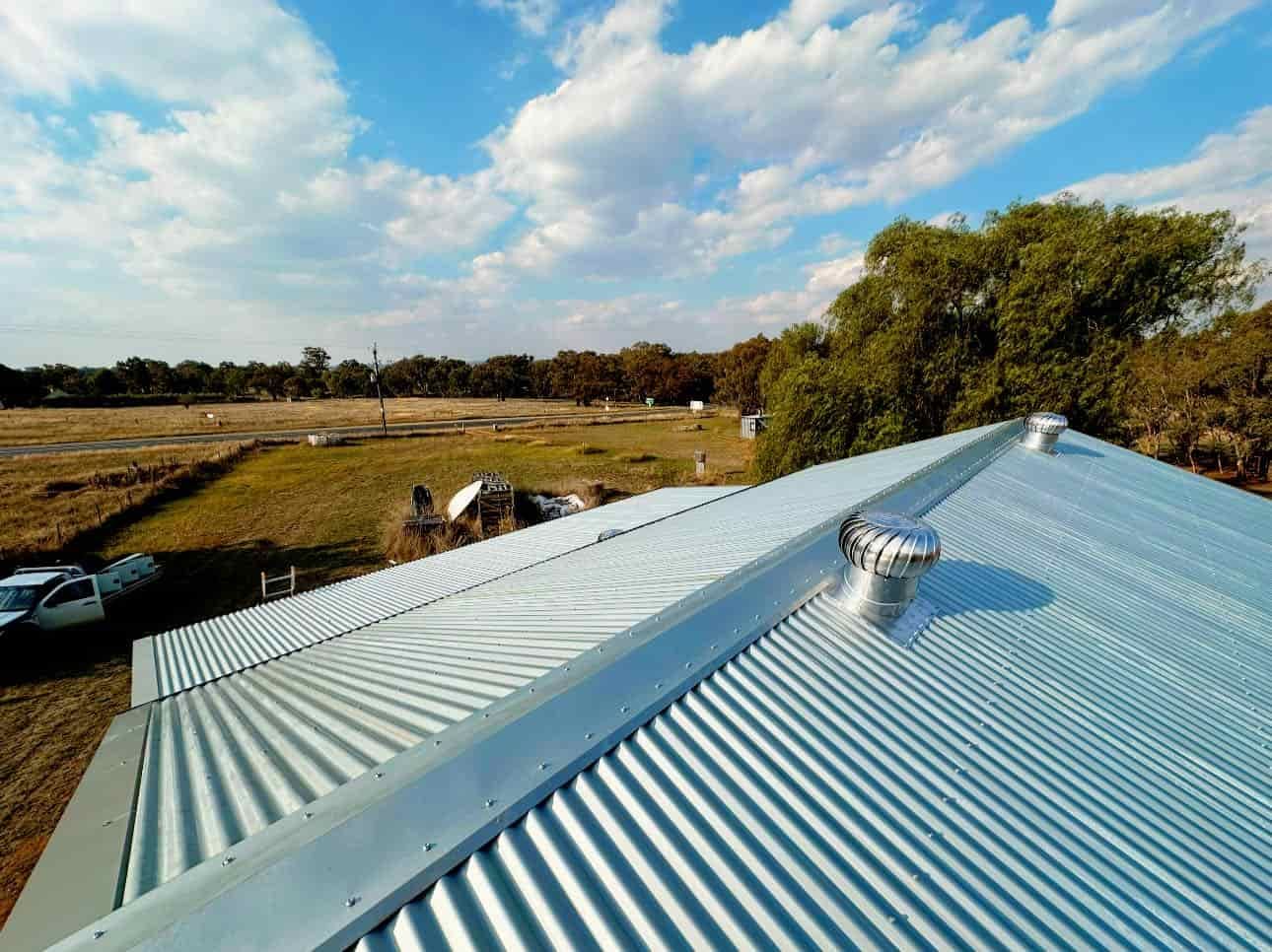 An Aerial View of a Metal Roof With Trees in the Background — Essential Roofing and Plumbing in Narrandera, NSW
