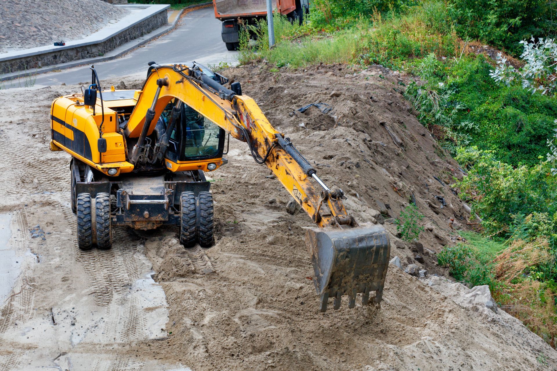 a construction excavator clears a construction site for the foundation of a future home.