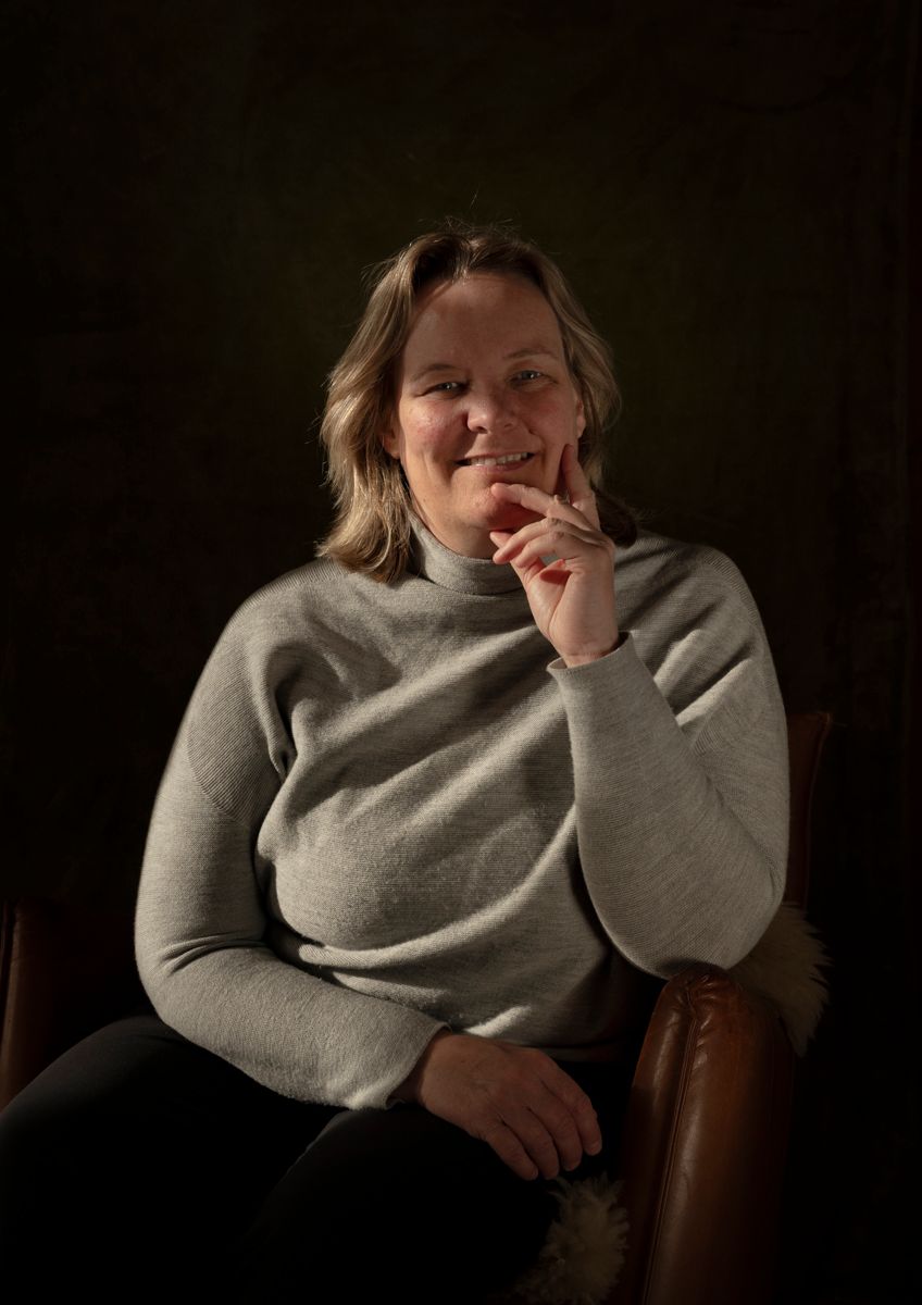 Een vrouw zit in een stoel met haar hand op haar kin.