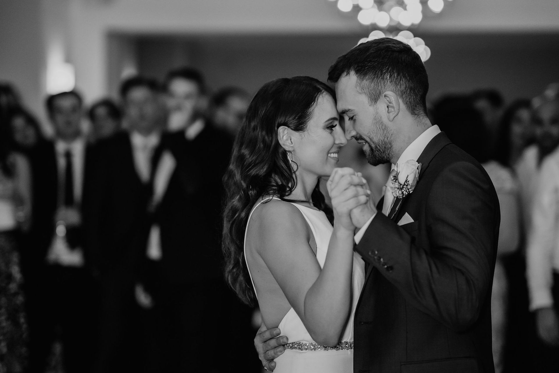 A black and white photo of a bride and groom dancing at their wedding reception.
