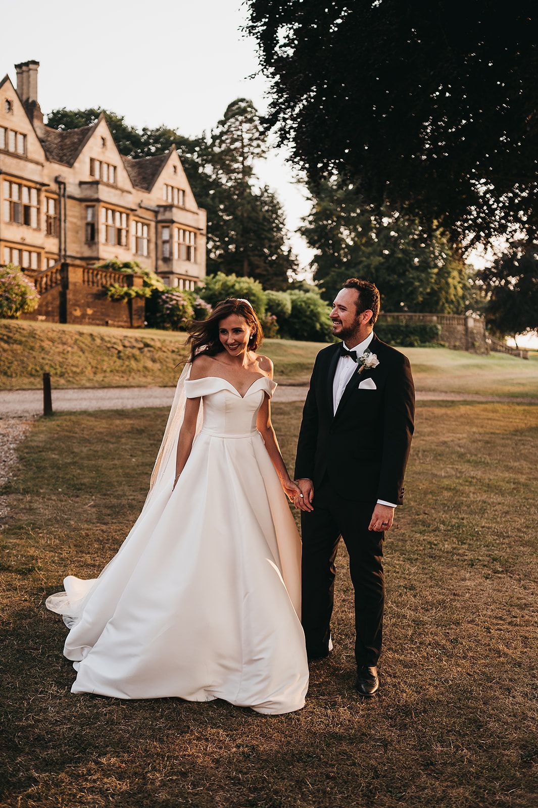 A bride and groom are holding hands in front of a large building.