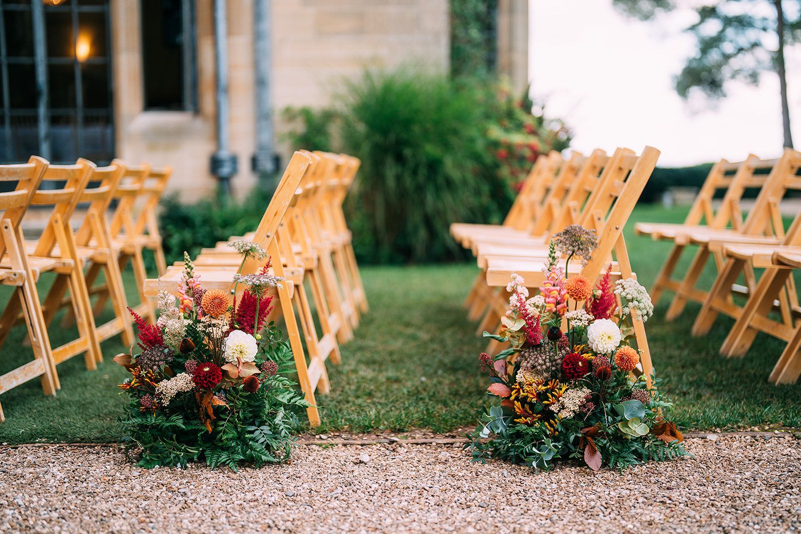 A row of wooden folding chairs with flowers in front of them.