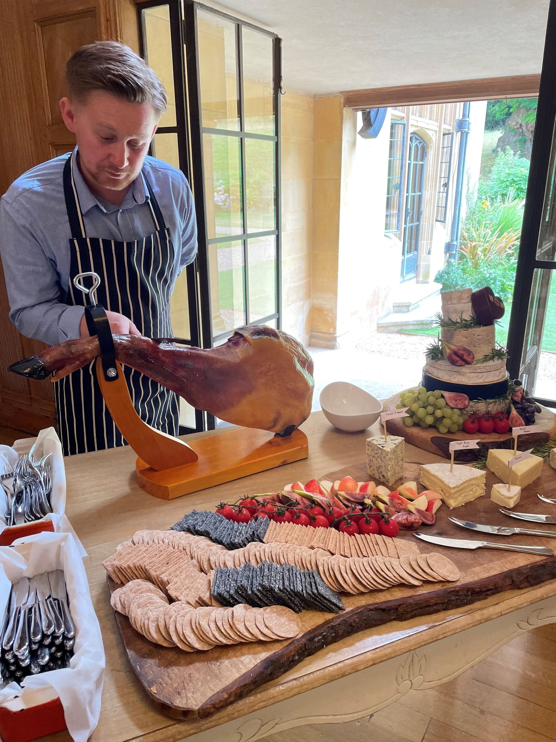 A man is cutting a piece of ham on a cutting board.