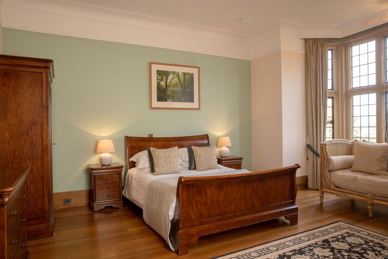 A bedroom with a sleigh bed , a couch , nightstands , and a picture on the wall.