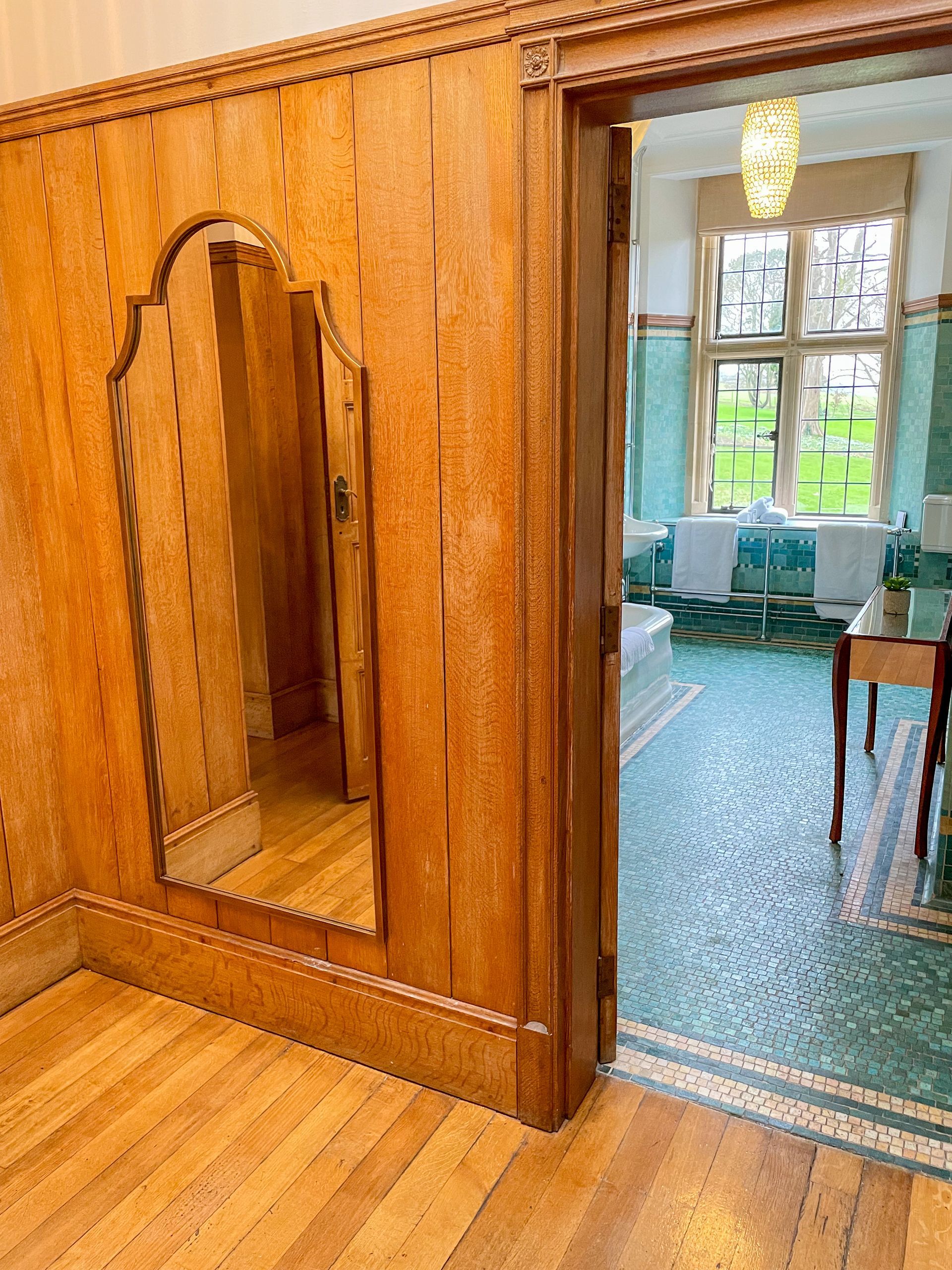 A room with a large mirror on the wall and a wooden floor.
