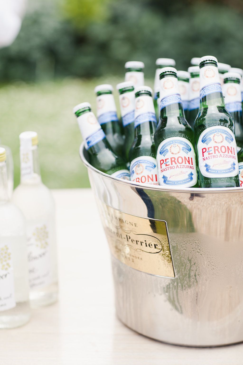 A bucket filled with bottles of peroni beer is sitting on a table.