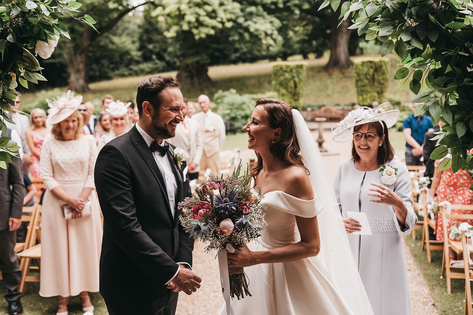 A bride and groom are laughing while walking down the aisle at their wedding.