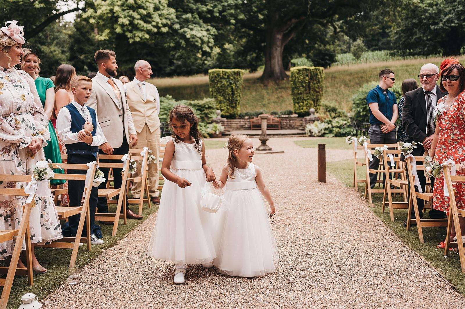 Two flower girls are walking down the aisle at a wedding holding hands.