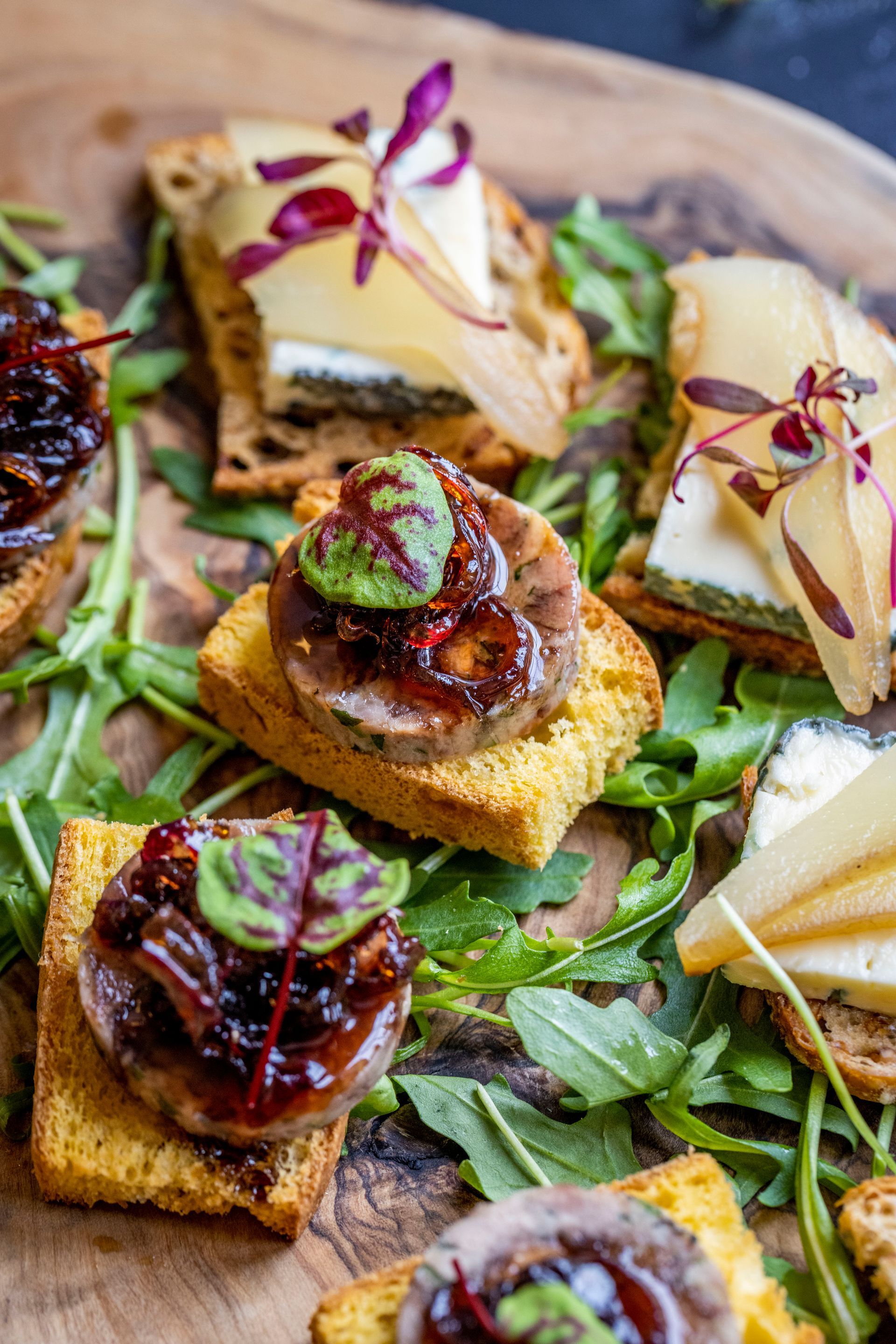 A wooden cutting board topped with a variety of appetizers.
