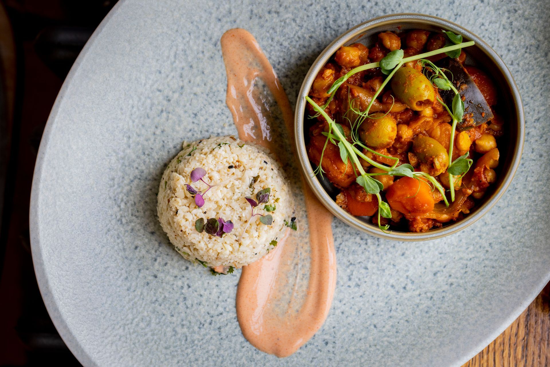 A plate of food with rice and a bowl of food on a table.