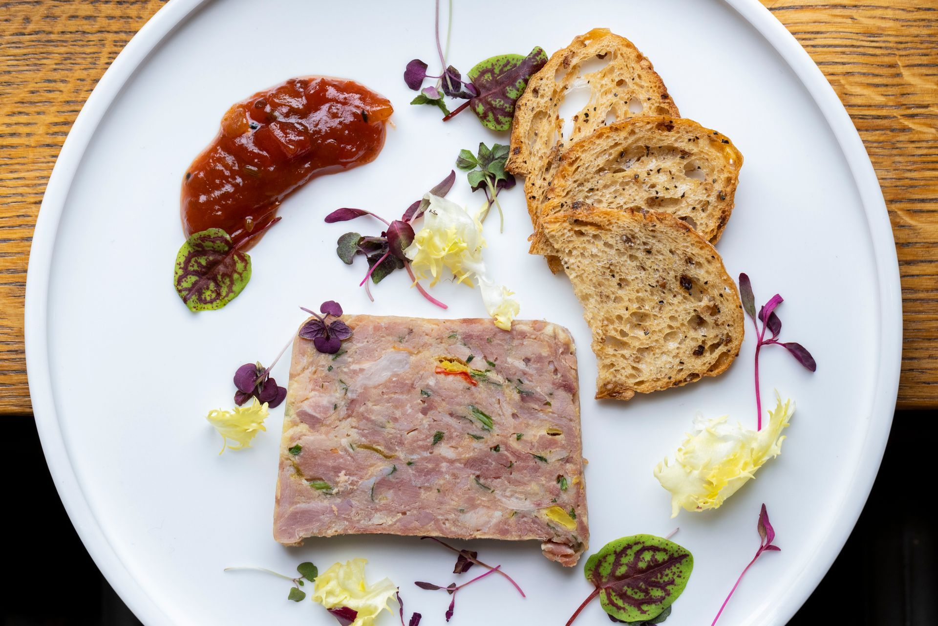 A white plate topped with meat and bread on a wooden table