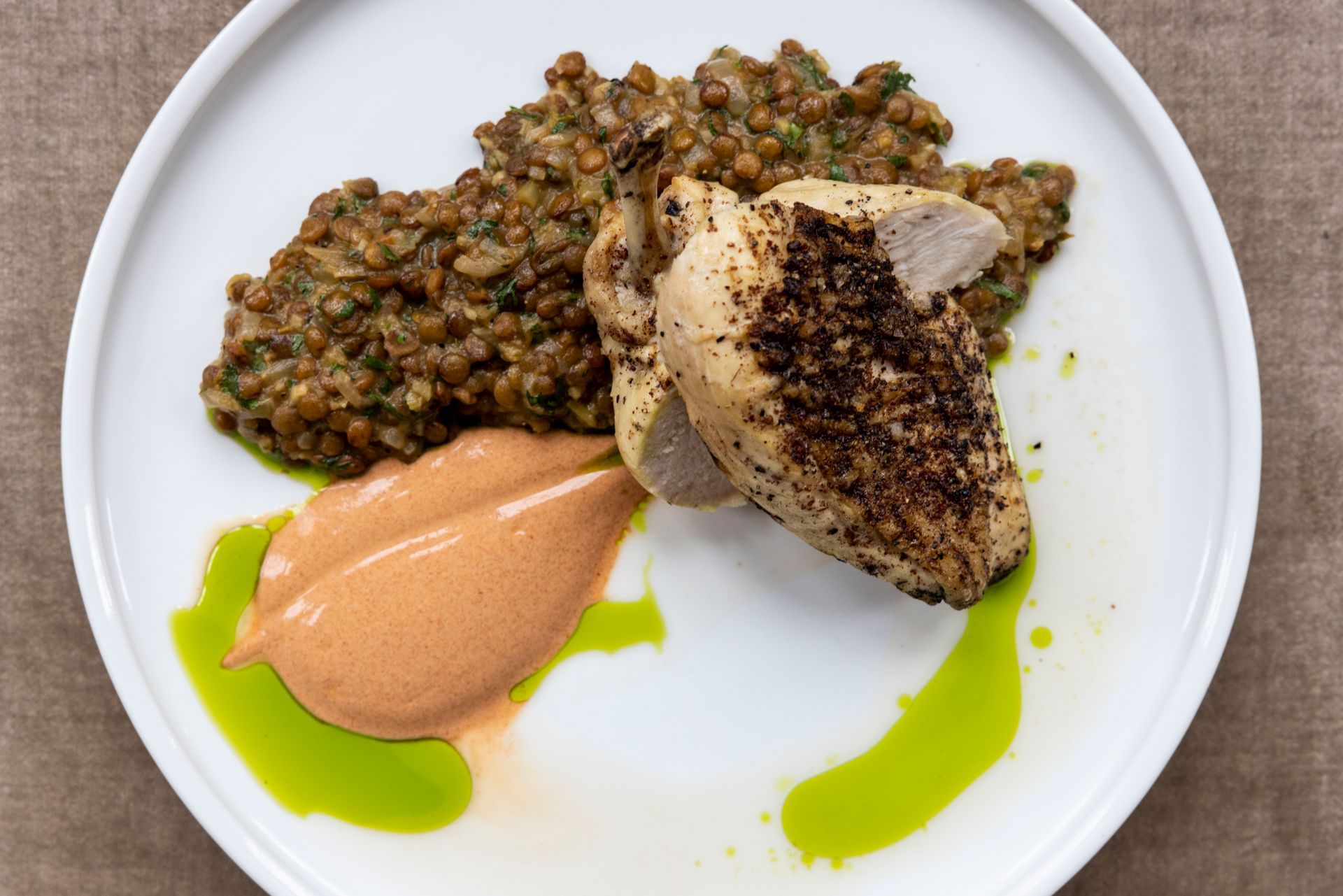 A white plate topped with chicken , lentils and sauce.