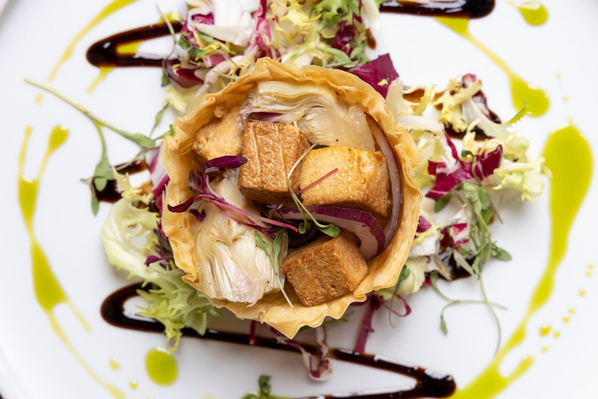 A white plate topped with a salad and a pastry