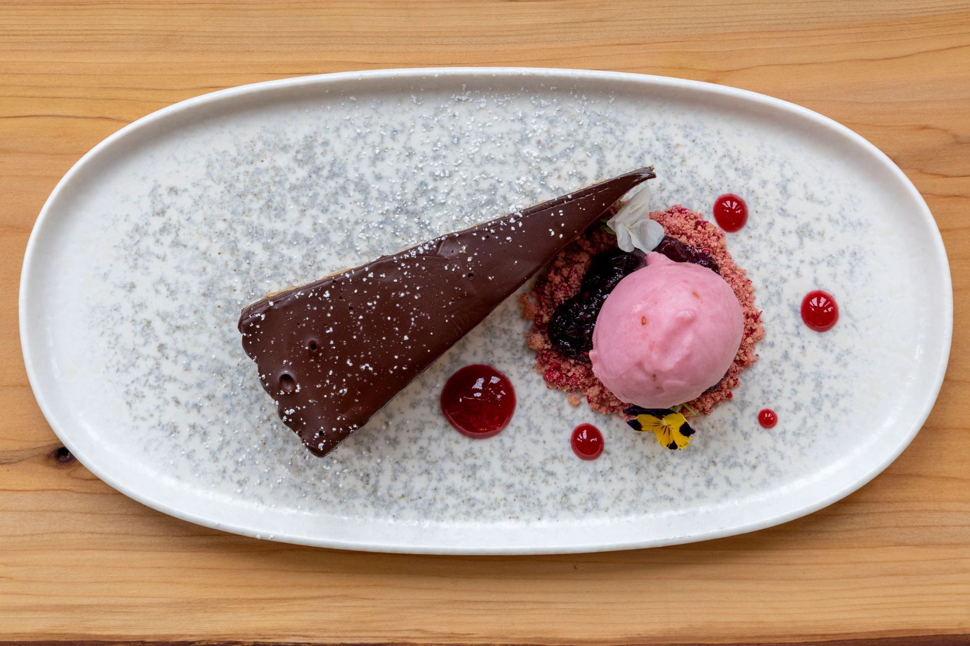 A white plate topped with a piece of chocolate cake and a scoop of pink ice cream.