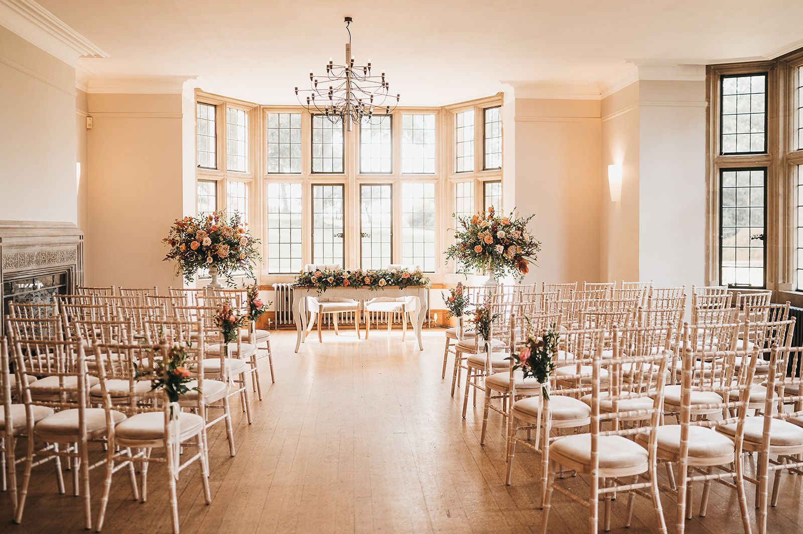 A room filled with chairs and flowers for a wedding ceremony.