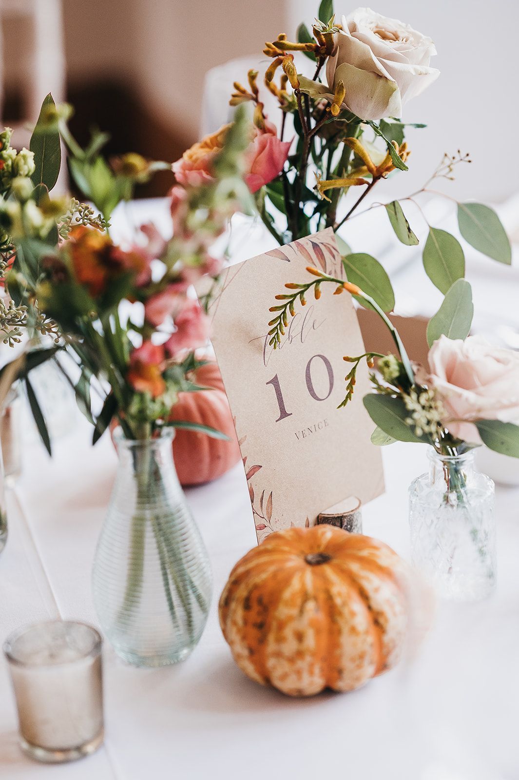 A table with a vase of flowers and a pumpkin on it.