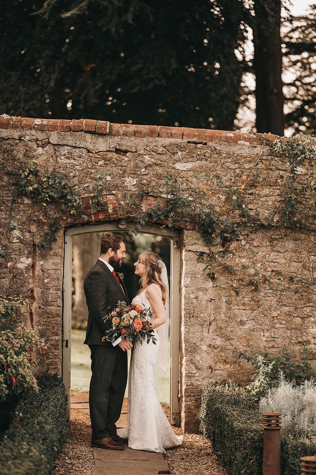 A bride and groom are standing in front of a brick wall.