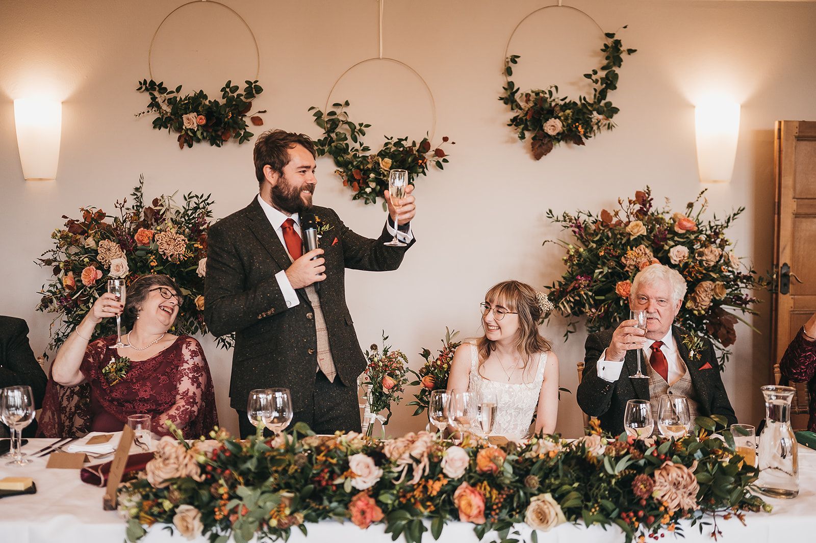 A man is giving a speech to a group of people at a wedding reception.