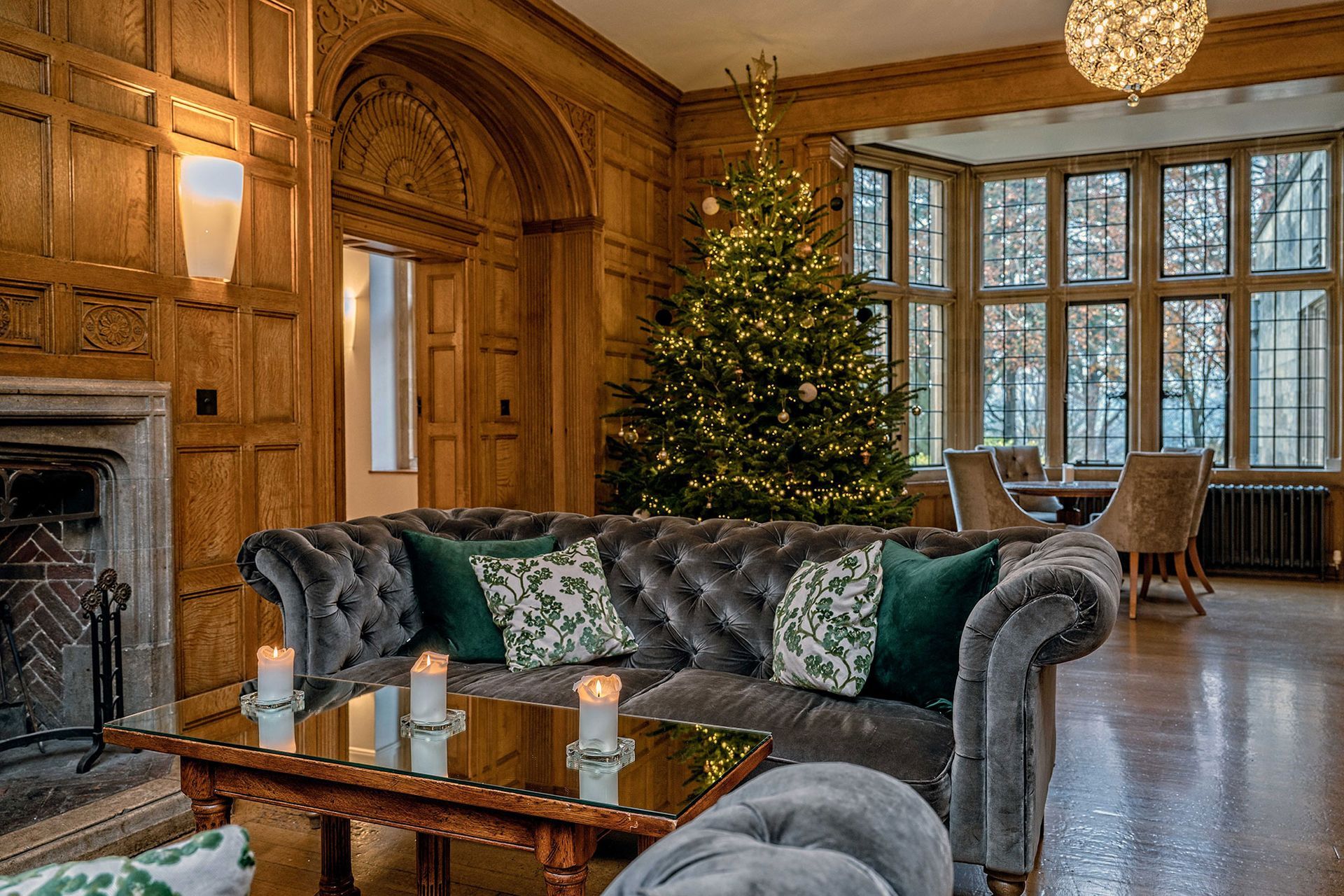 A living room with a couch , table , fireplace and christmas tree.
