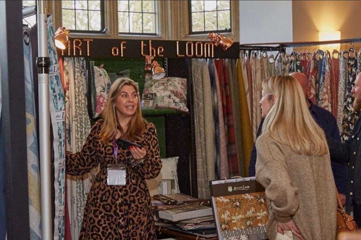 A woman in a leopard print dress is standing in front of a display of fabrics.