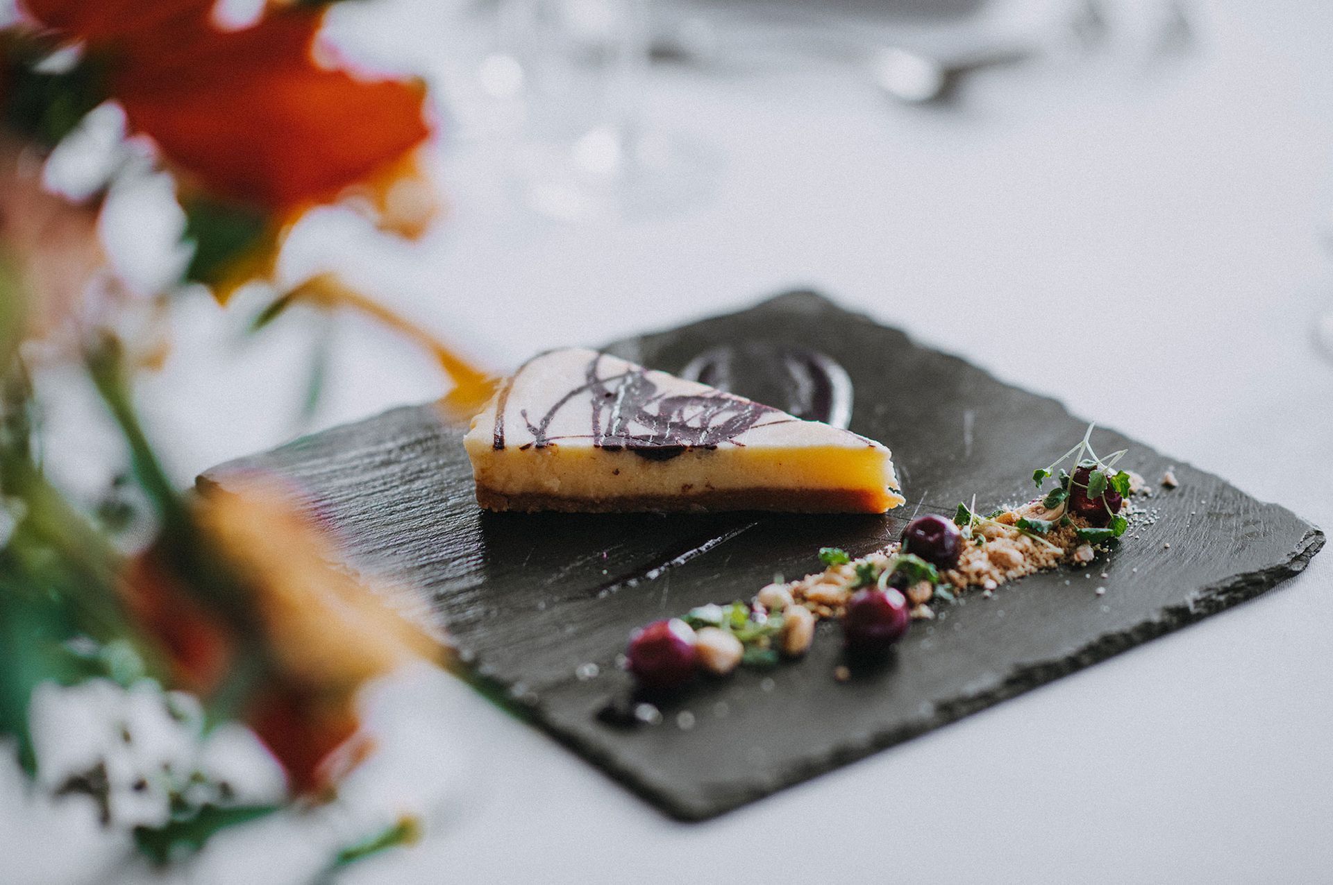 A slice of cheesecake is on a slate plate on a table.