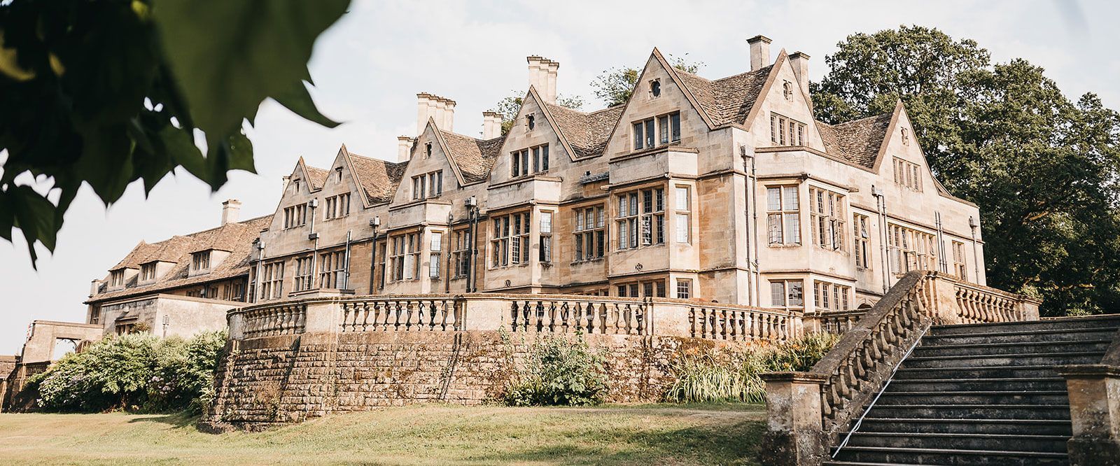 A large stone building with stairs leading up to it is surrounded by trees.