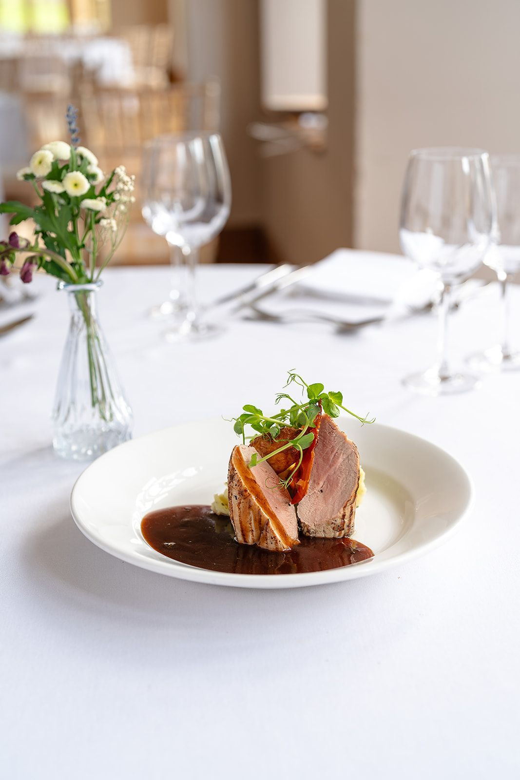 A plate of food is sitting on a table next to a vase of flowers.