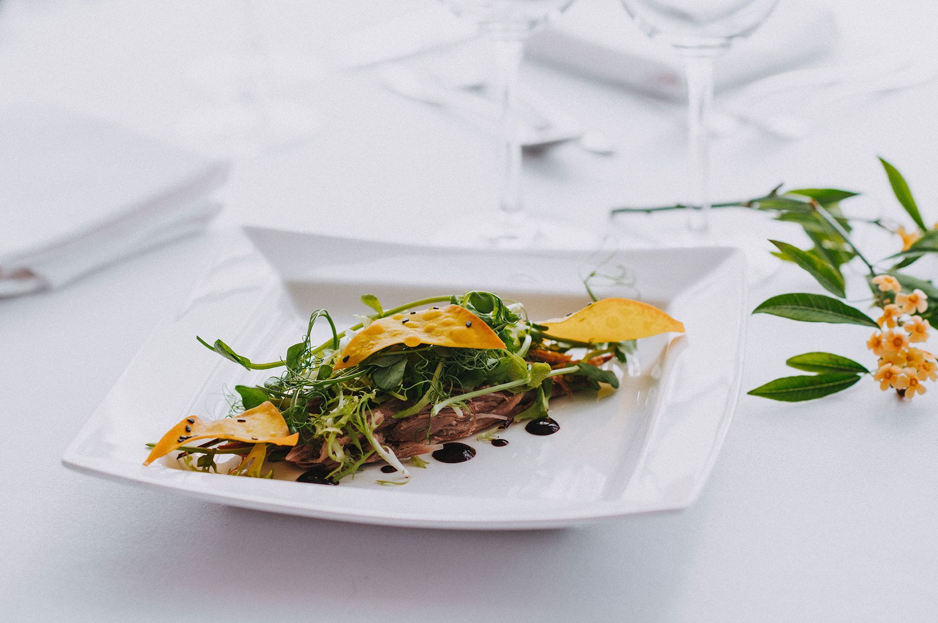 A white plate topped with a salad on a table.