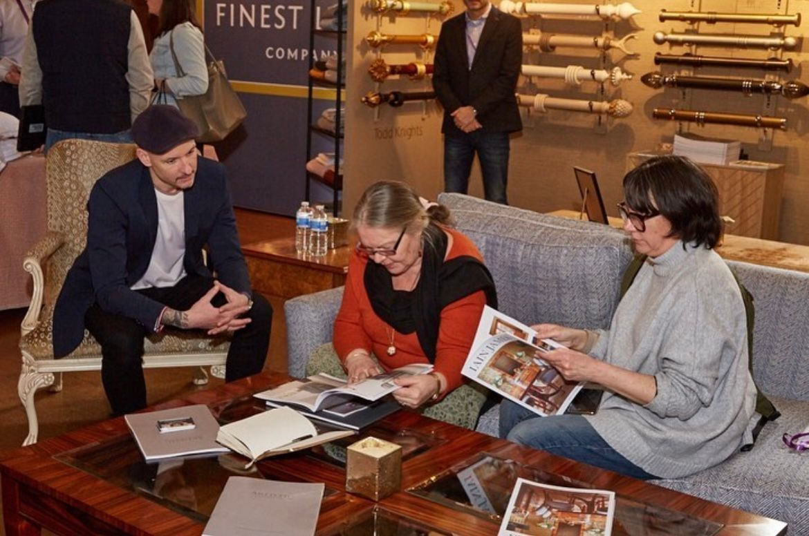 A group of people are sitting around a table looking at magazines.