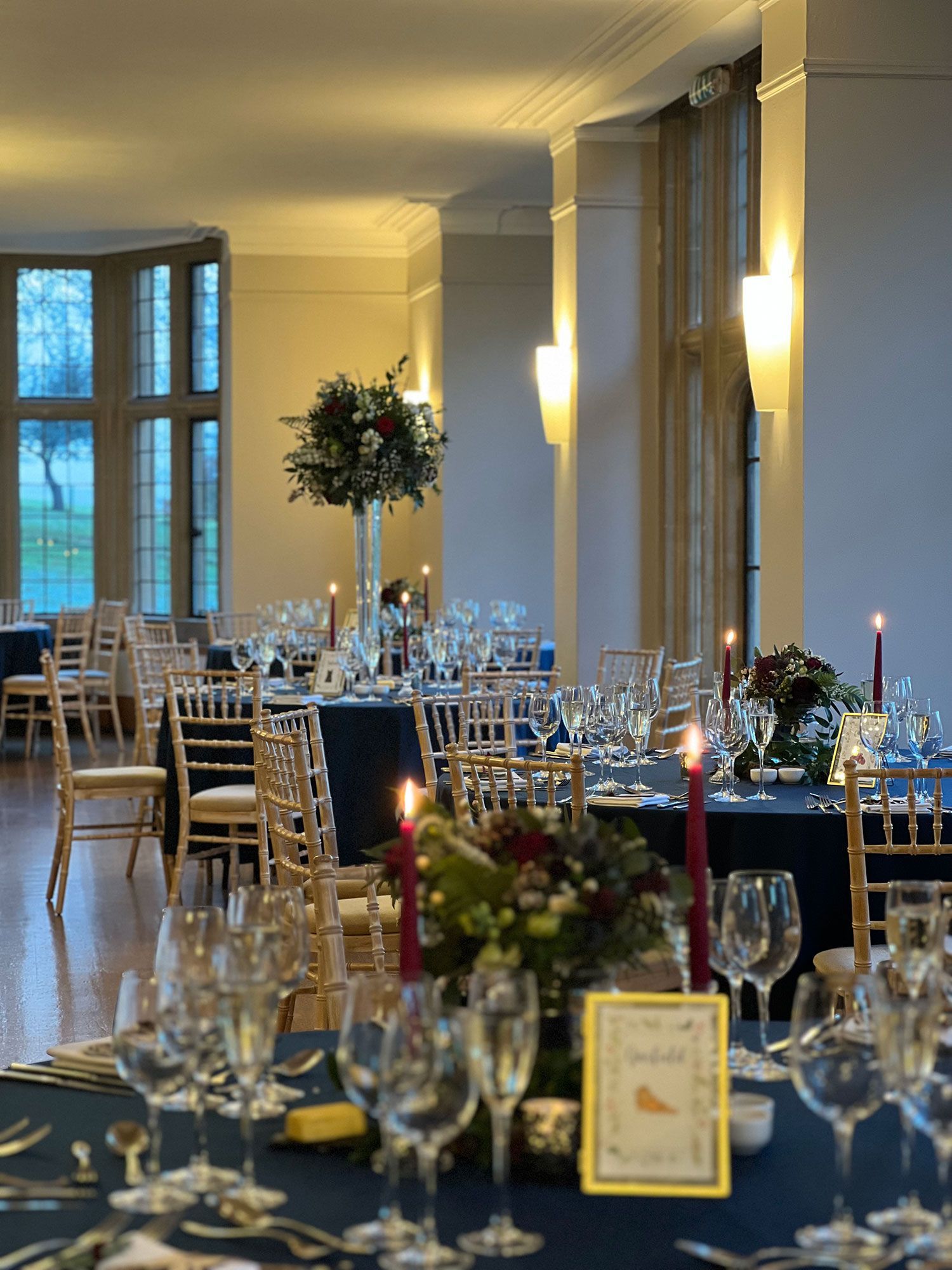 A large room with tables and chairs set up for a wedding reception