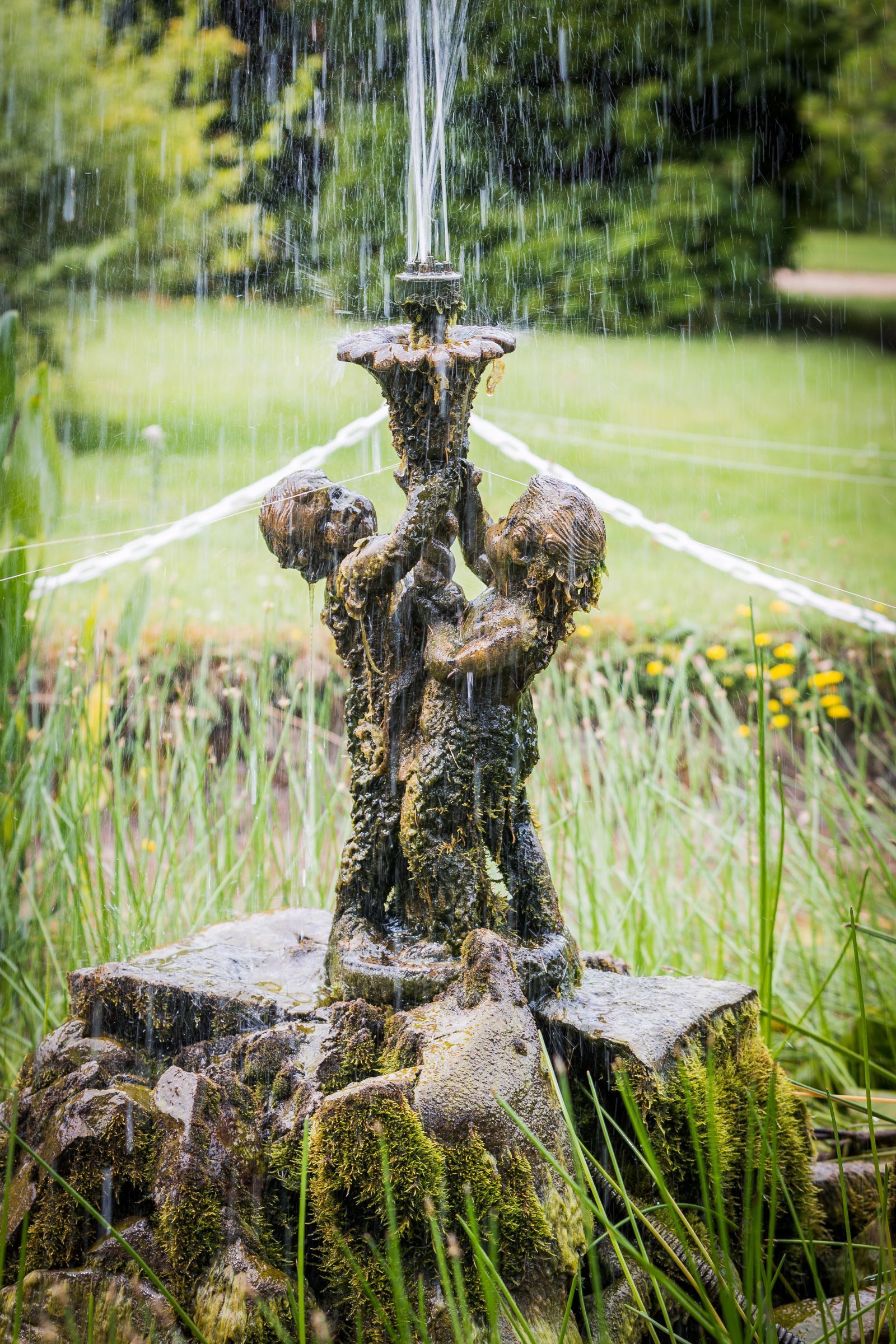 A fountain with a statue of two children holding a candle in a garden.