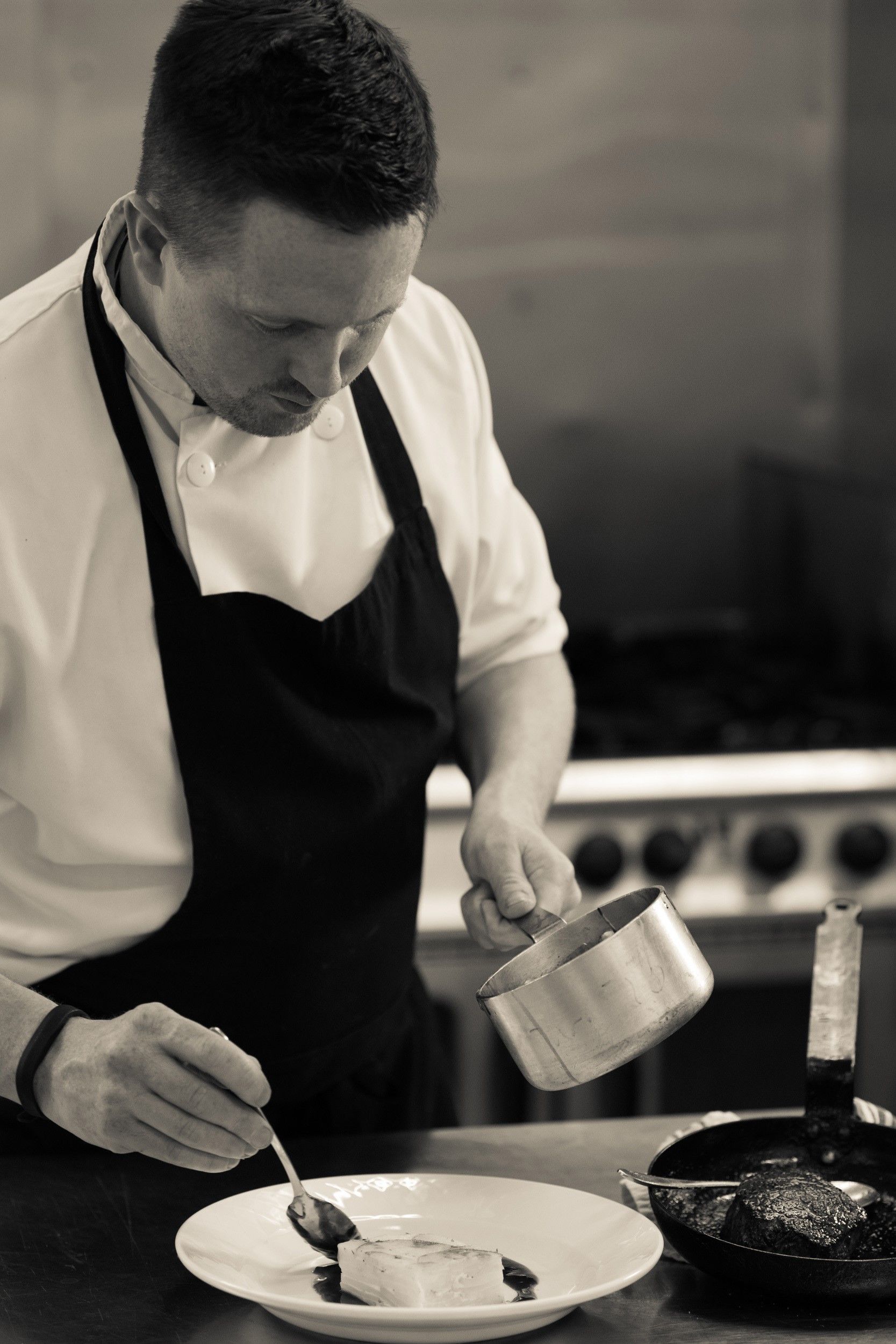 A man in an apron is preparing food in a kitchen.