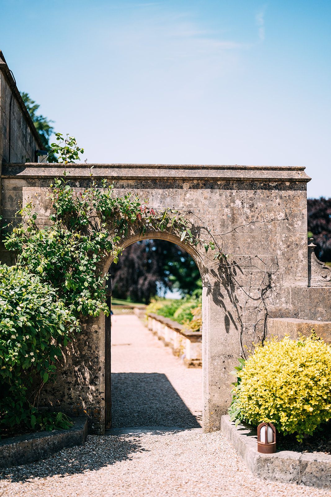 There is a stone archway leading to a garden.