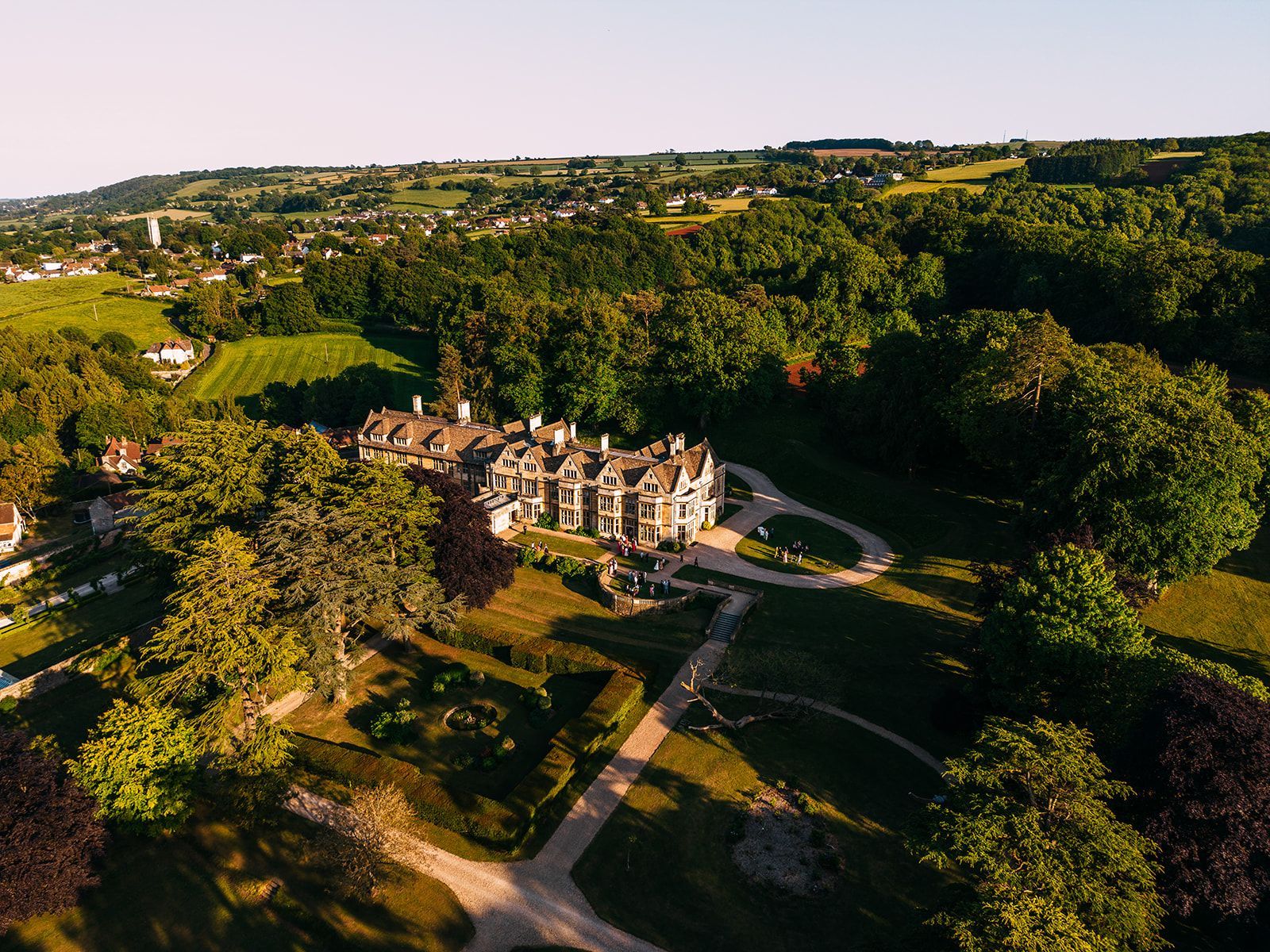 An aerial view of a large house surrounded by trees and grass.