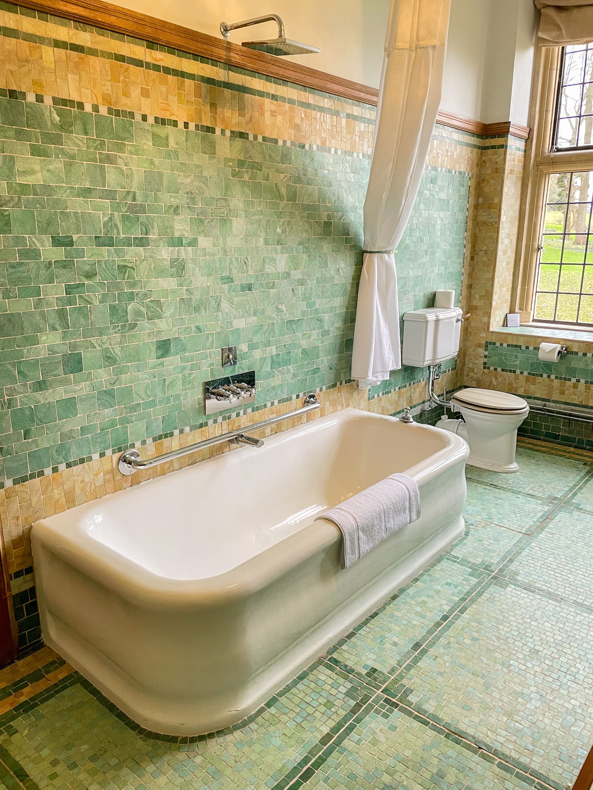 A bathroom with a bathtub , toilet and window.