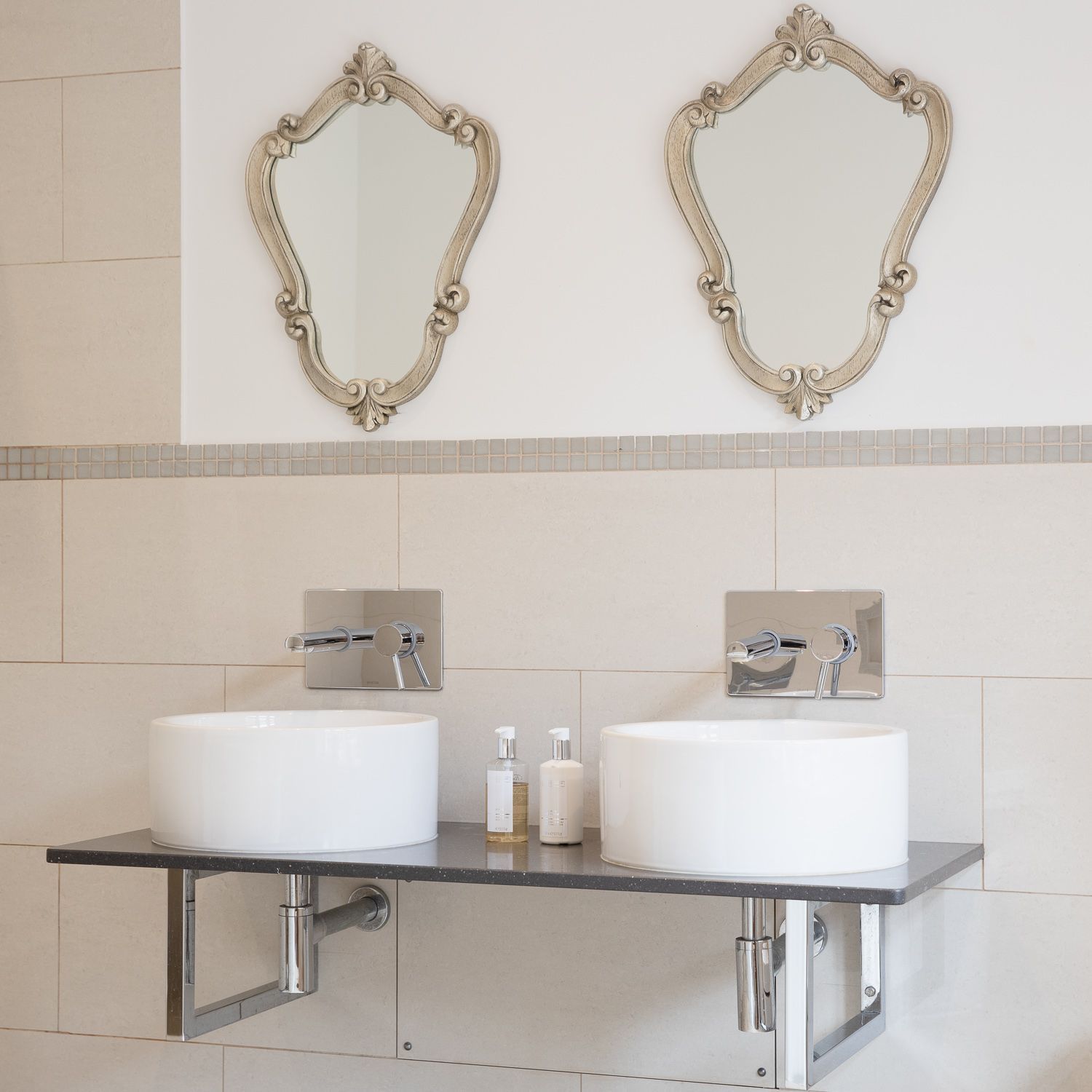 A bathroom with two sinks and two mirrors on the wall