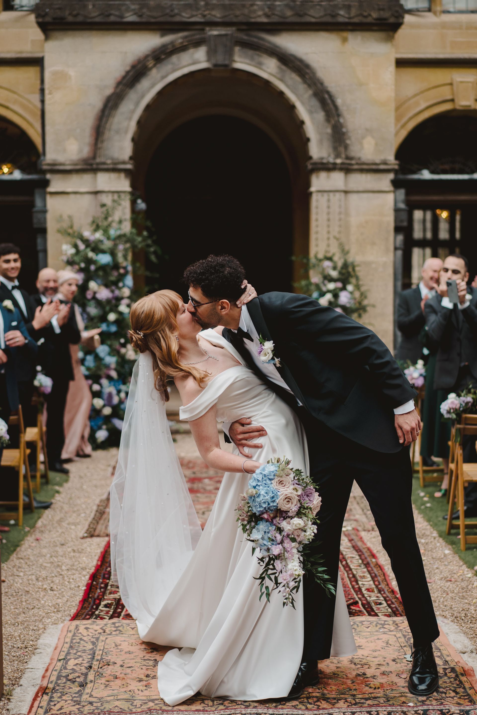 A bride and groom kissing on the aisle at their wedding.