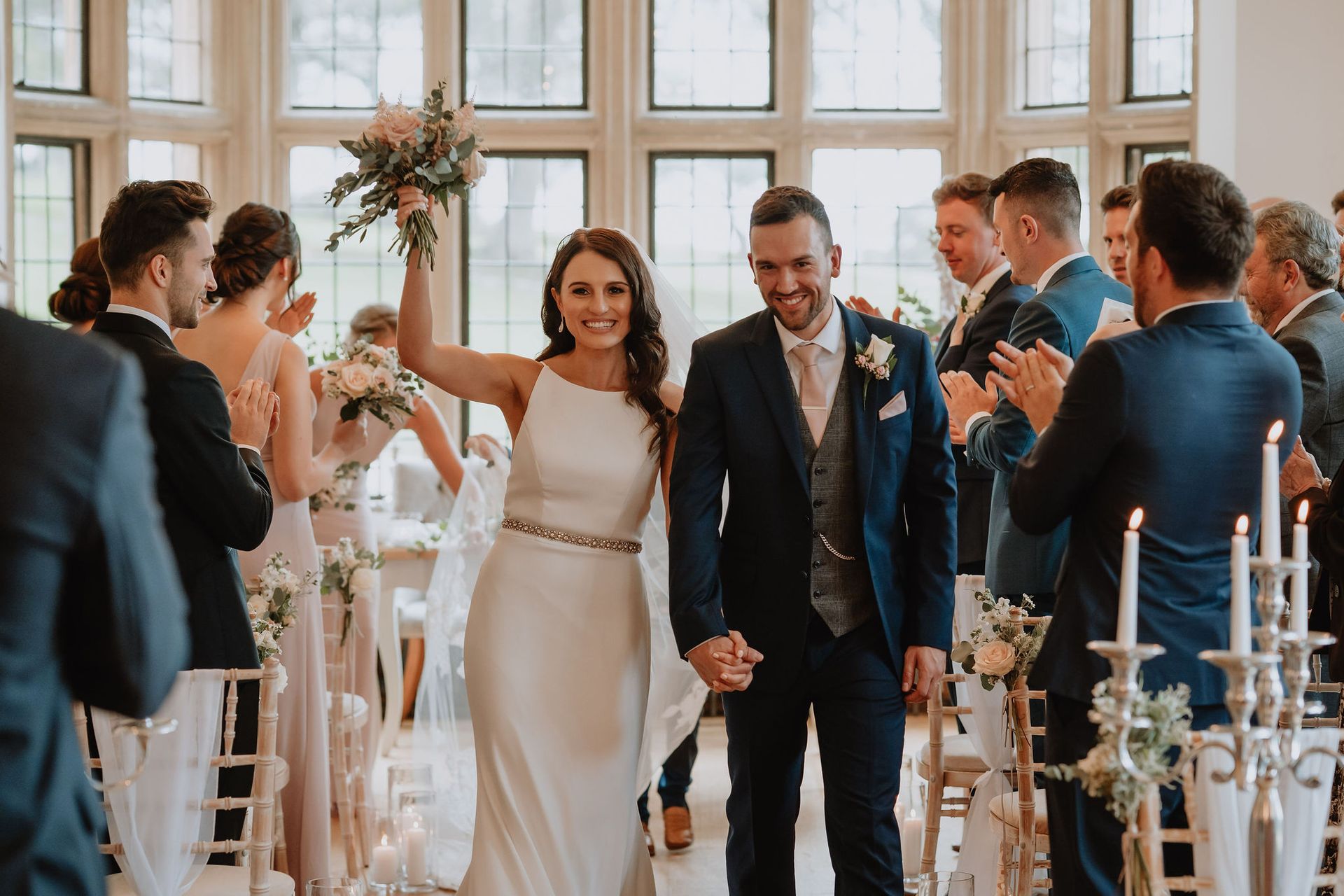 A bride and groom are walking down the aisle at their wedding holding hands.
