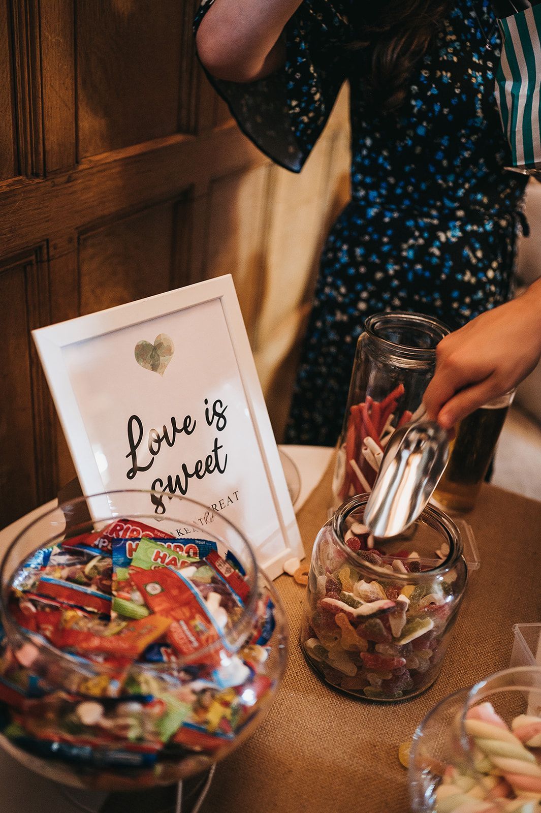A woman is putting candy in a jar on a table.