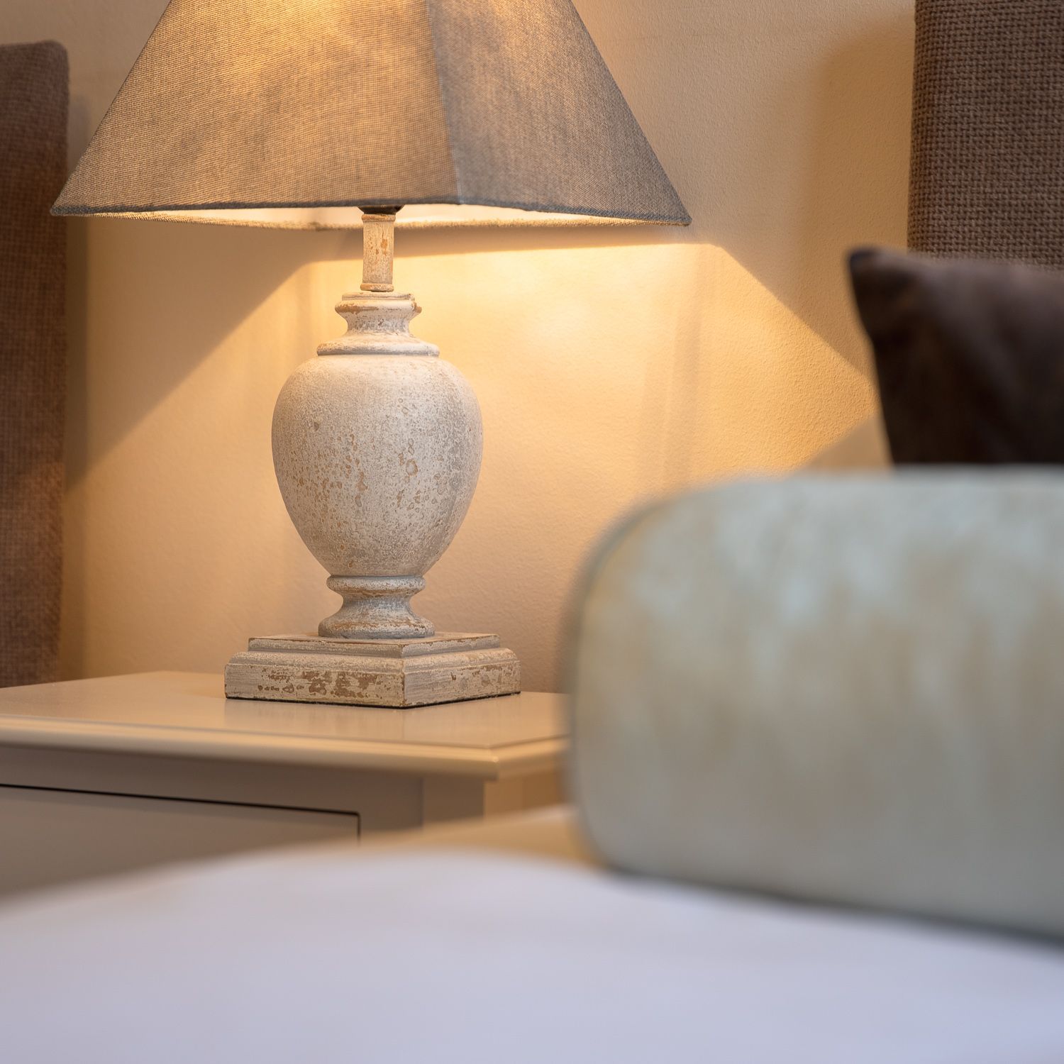 A lamp sits on a nightstand next to a bed