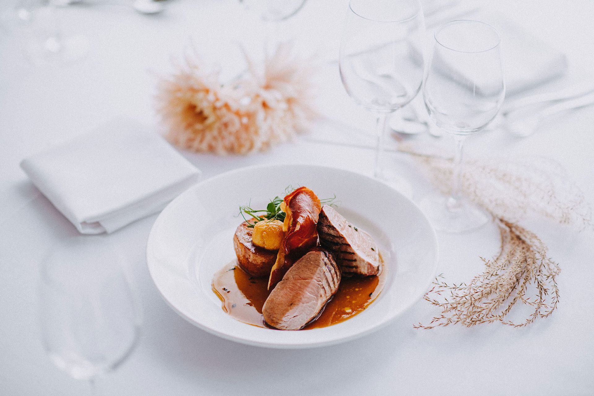 A white plate topped with meat and sauce on a table.