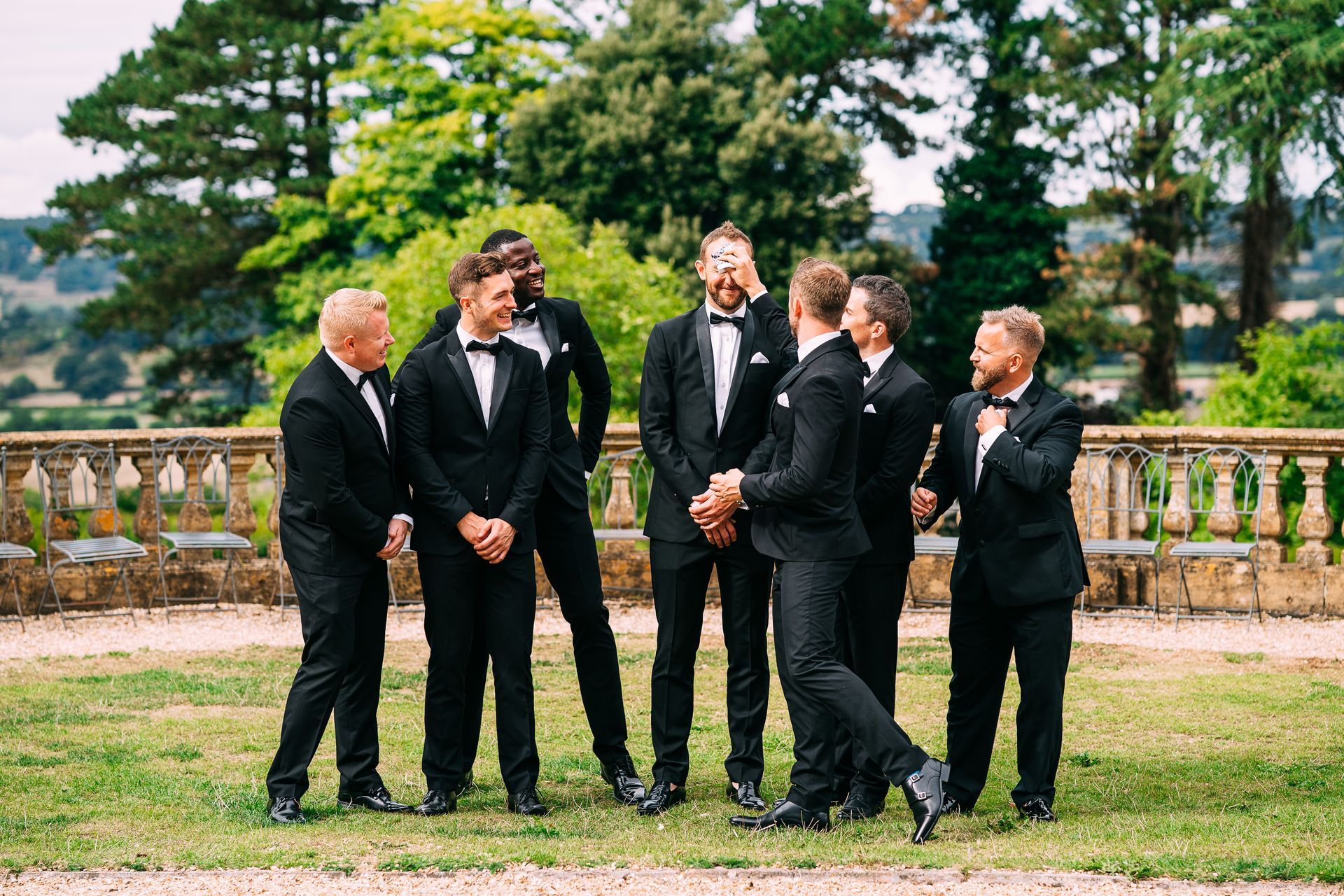 A group of men in tuxedos are standing in a field.