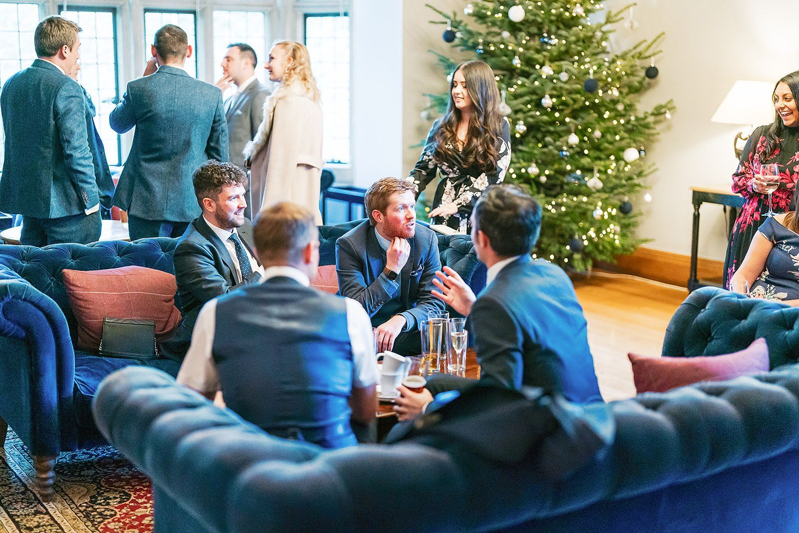 A group of people are sitting on couches in front of a christmas tree.