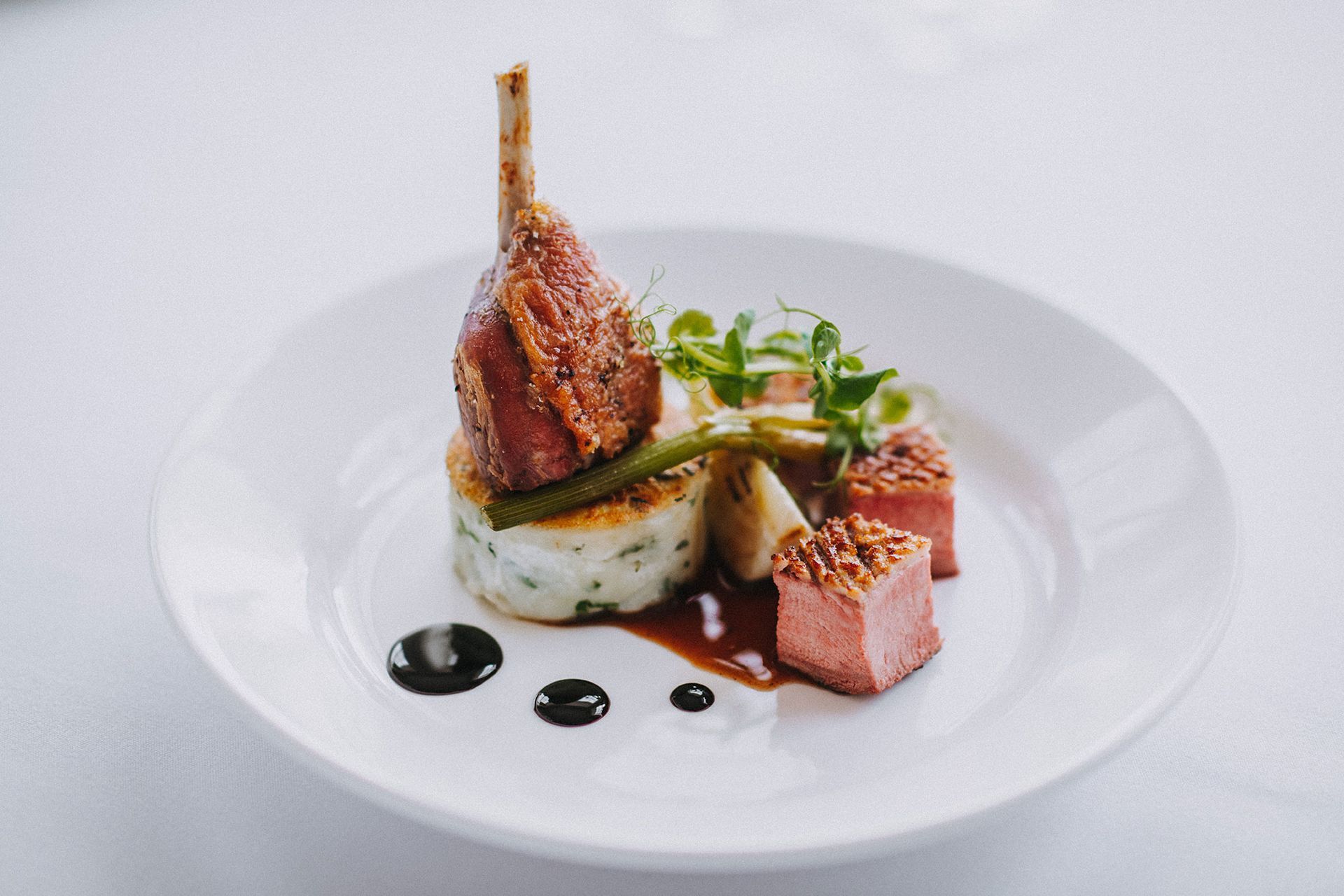 A white plate topped with meat and vegetables on a table.