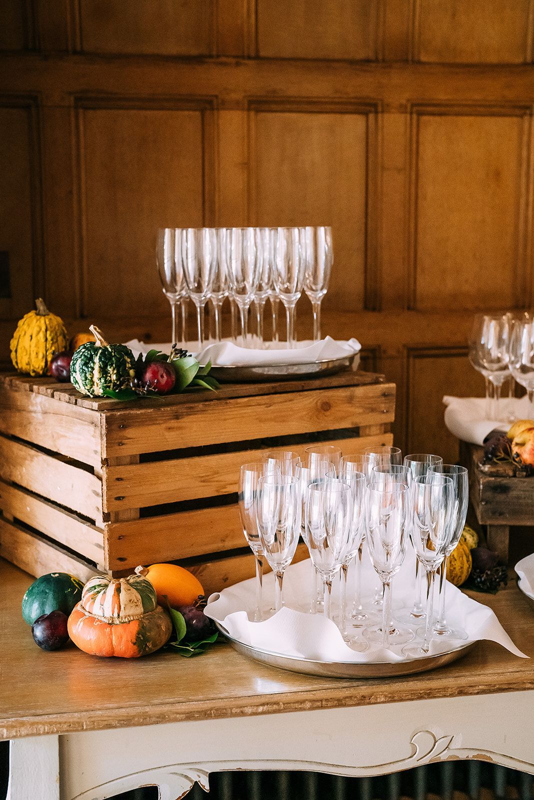 A wooden crate filled with wine glasses and pumpkins on a table.