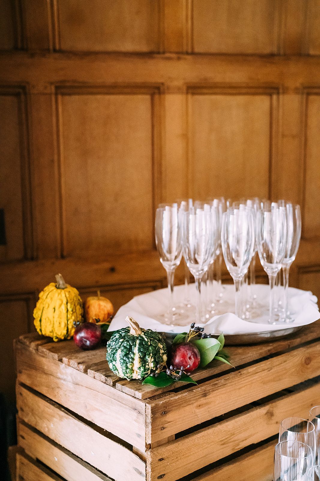 A wooden crate filled with wine glasses and pumpkins.
