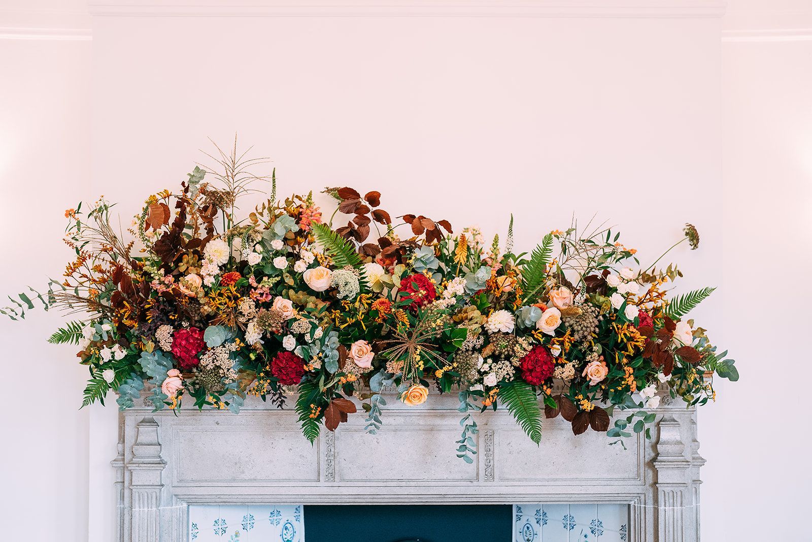 A mantle decorated with flowers and leaves on a wall.