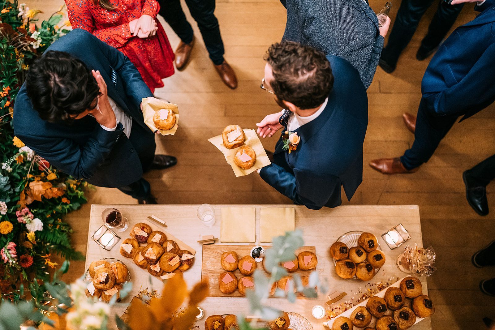 A group of people are standing around a table filled with food.