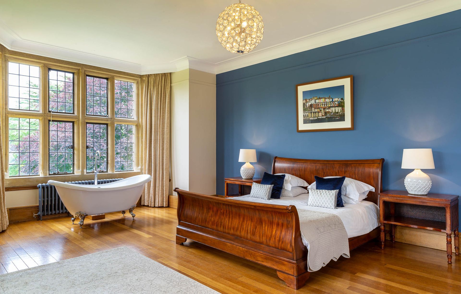 A bedroom with a bed , bathtub and blue walls.